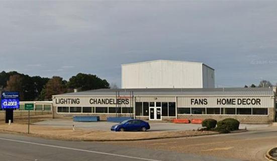 Former retail lighting store in Bono, Arkansas known as The Lamp Outlet showing large building, parking lot with a car in it, and a large store sign.