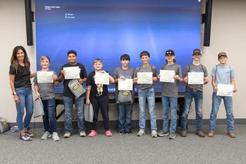Students standing in a row holding their TekStarz completion certificates 